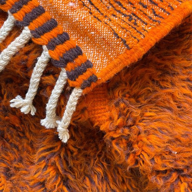 Franges tressées d'un tapis orange en plein soleil